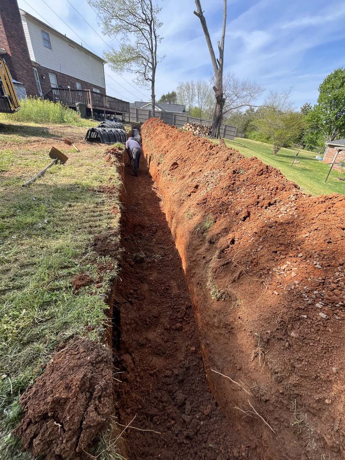 Deep drainage trench being dug in a backyard