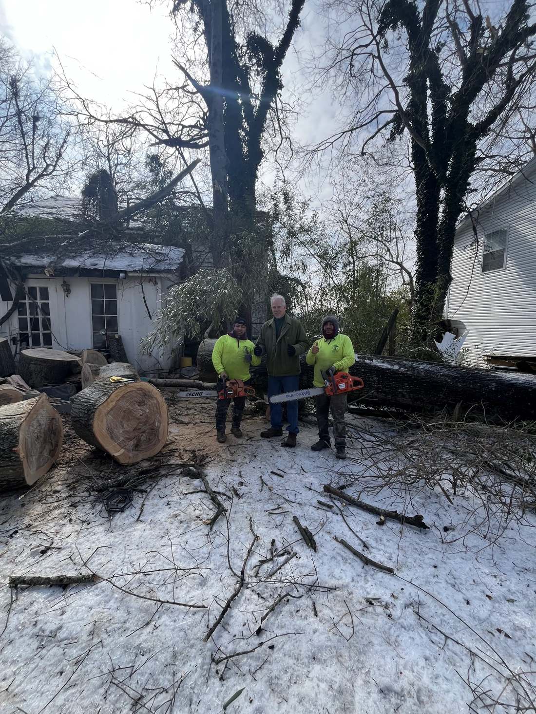 Crew posing with chainsaws after a winter storm cleanup