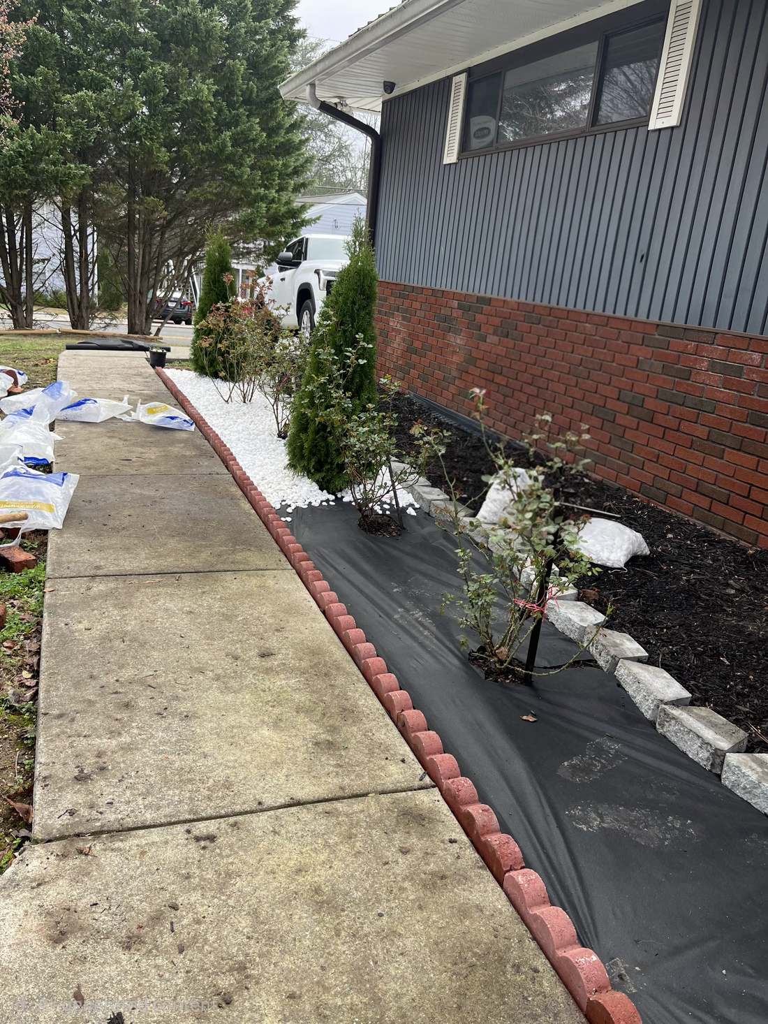 Finished landscape bed with white rock and brick border